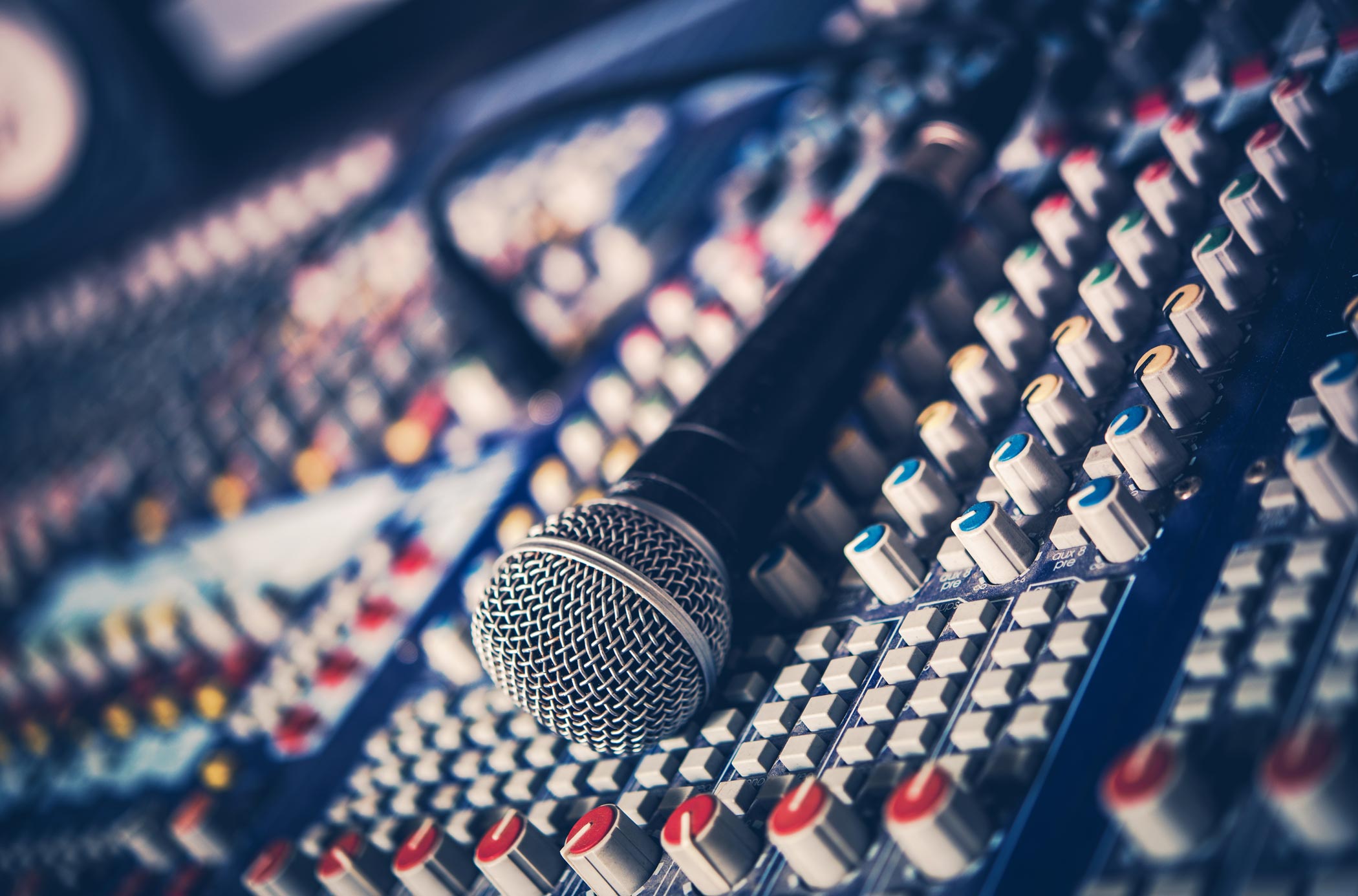 Music mixing desk with a microphone resting on the mixer